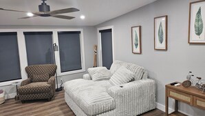 Un dormitorio con cama, una silla, piso de madera y ventilador de techo.