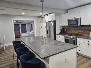 Eine moderne Küche mit weißen Schränken, einer Arbeitsplatte aus Granit und einem Edelstahl-Kühlschrank.