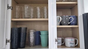 Un armario de cocina con diferentes vasos, tazas y recipientes.