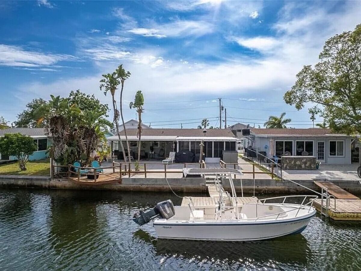 A boat docked at a marina with a house in the background.