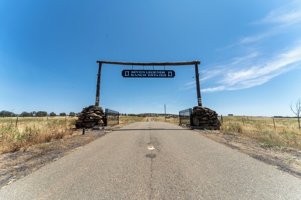 A rural road leading to a gated entrance labeled "Seven Legends Ranch Estates."