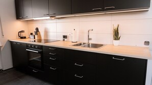 A modern kitchen with black cabinets, a stainless steel sink, and a built-in oven.