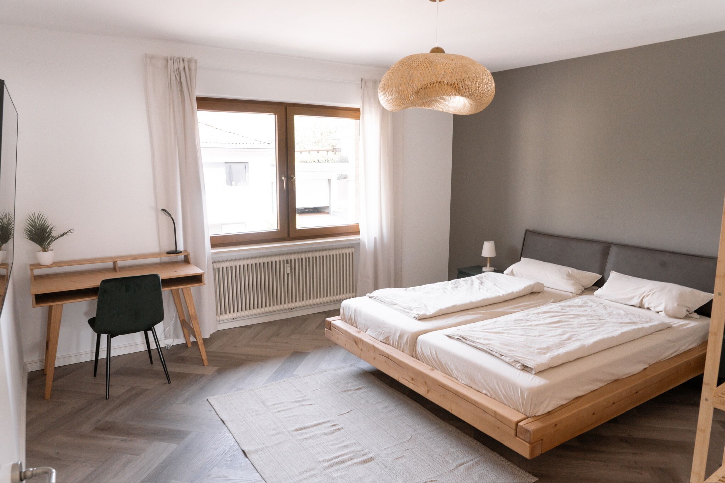 Quarto moderno com cama de madeira, uma escrivaninha e uma cadeira.