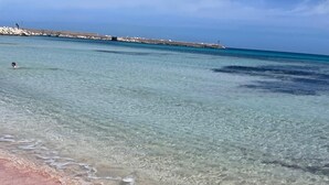 Una playa con aguas poco profundas y cristalinas y una orilla arenosa.