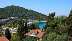 A coastal town with a beach, buildings, and a hill in the background. - A3 KABLAR'S SUNNY SUITES 1BR APT with balcony and sea view - Duplicate (Dubrovnik)