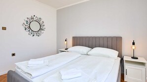 A neatly made bed with white linens and two bedside tables with lamps. - A3 KABLAR'S SUNNY SUITES 1BR APT with balcony and sea view - Duplicate (Dubrovnik)