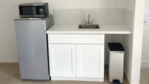 A compact kitchen with a microwave, sink, and a coffee maker on a shelf. - Rommar Cozy Suite (CAY HILL ,LITTLE BAY)