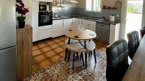 A modern kitchen with white cabinets, a built-in oven, and a dining area with a round table and chairs.