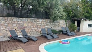 A poolside area with lounge chairs and a stone wall.