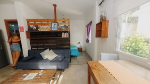 Ein Wohnzimmer mit einem blauen Sofa, einem Holztisch und einem Wagen voller Zeitschriften.
