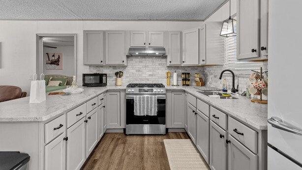 Una cocina moderna con armarios blancos, estufa de acero inoxidable y microondas.