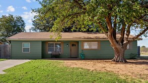 Una casa de un piso con fachada verde, una puerta principal y un pequeño porche.