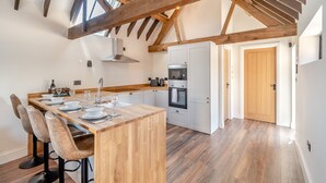 Une cuisine moderne avec des poutres en bois, un îlot central et un four encastré.