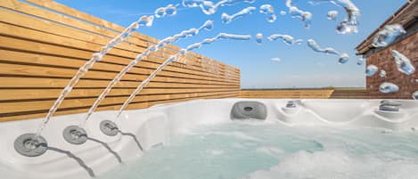 A hot tub with water jets, surrounded by wooden slats and a brick wall.