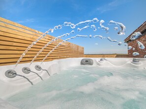 Un jacuzzi con chorros de agua, rodeado de listones de madera y un muro de ladrillo.