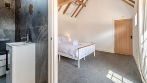 Une chambre à coucher avec un lit, une porte en bois et un plafond en pente avec des poutres apparentes.