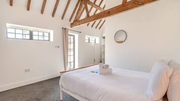 Un dormitorio con cama, ventana, espejo y techo con vigas de madera.