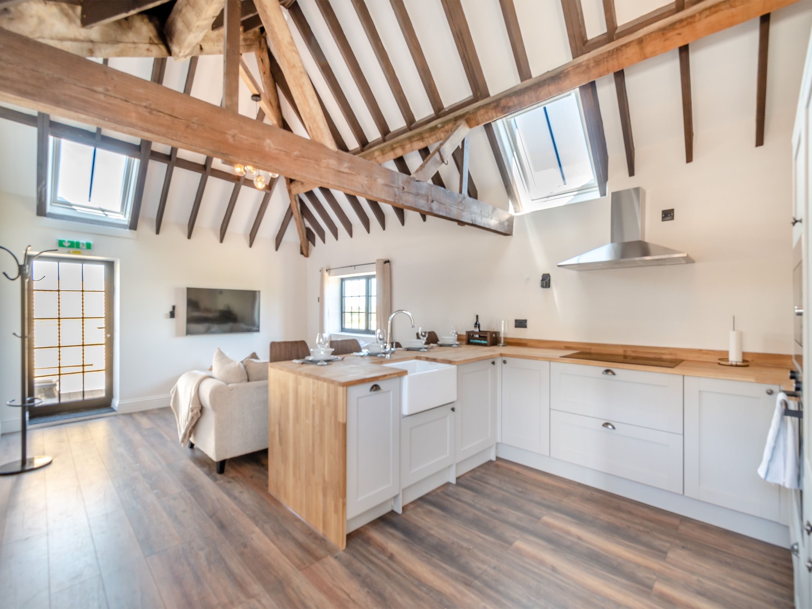 Una cocina moderna con vigas de madera, armarios blancos y una isla central.