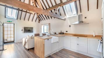 Una cocina moderna con vigas de madera, armarios blancos y una isla central.