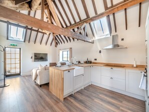 Una cocina moderna con vigas de madera, armarios blancos y una isla central.