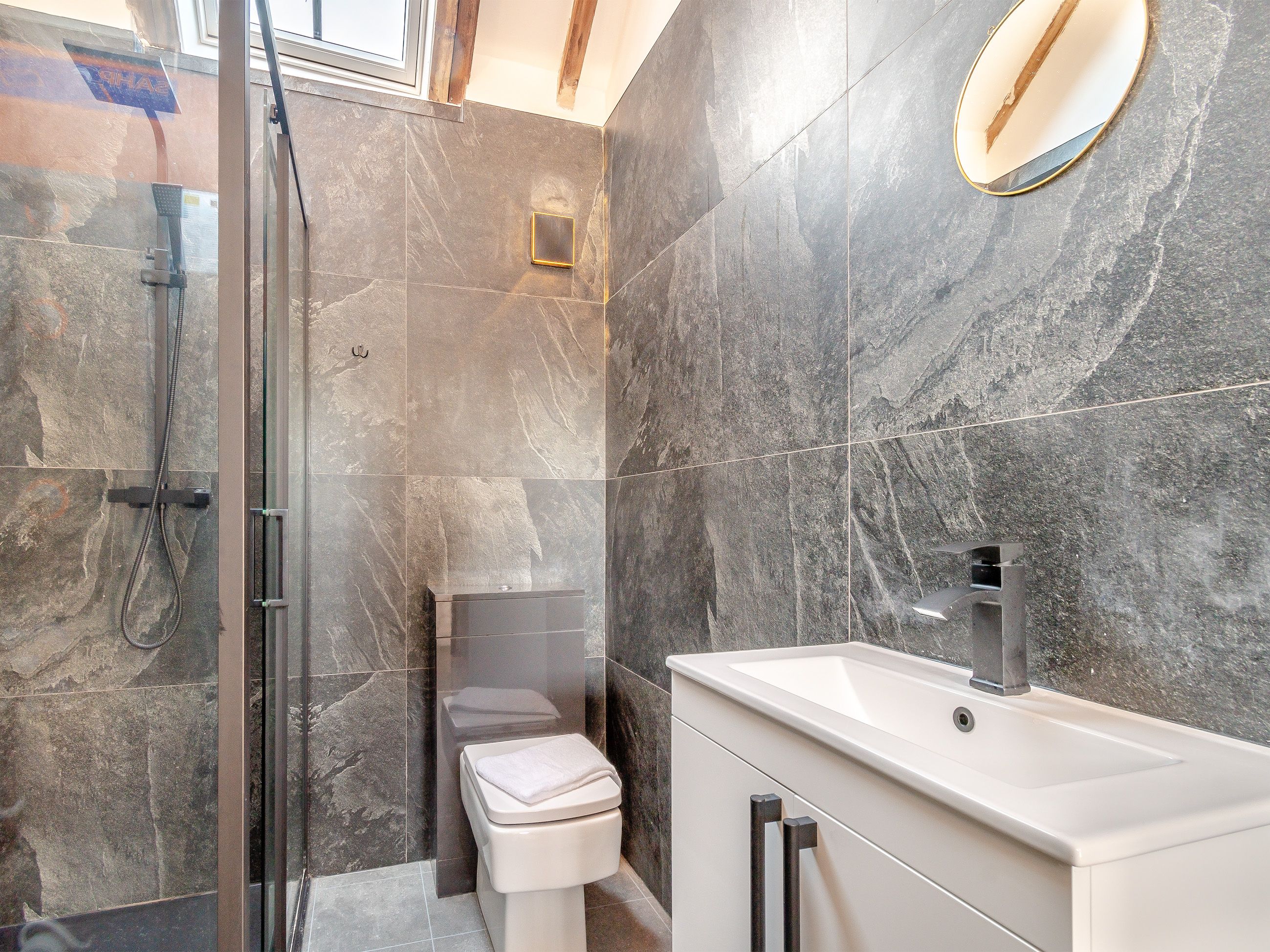 Une salle de bain moderne avec une douche à parois de verre, des toilettes et un meuble-lavabo avec un évier.