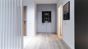 A hallway with a grey cabinet, a wooden door, and a framed artwork on the wall. - Luca (Bucharest)