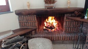 A fireplace with a fire, a wooden bench, and a small table with a keyboard. - 1 Bedroom Apartment in Procida (Procida)
