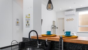 Eine moderne Küche mit einer Granit-Arbeitsplatte, einem schwarzen Wasserhahn und einem eingebauten Backofen. Auf der Arbeitsplatte stehen zwei blaue Tassen und eine schwarze Kaffeemaschine.