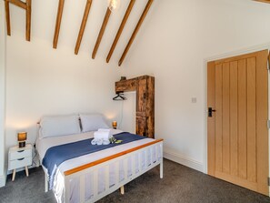 A bedroom with a wooden bed, white bedding, a nightstand with a lamp, and a wooden door. - Fountain Front Barn - UK45937 (Corley)