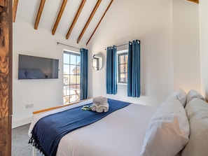 A bedroom with a large bed, a TV mounted on the wall, and a window with curtains. - Fountain Front Barn - UK45937 (Corley)