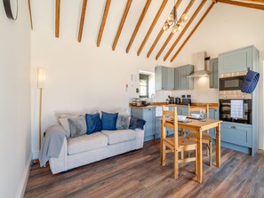 Una cocina moderna con vigas de madera, un comedor con mesa y sillas, y una sala de estar con sofá.