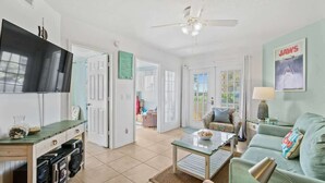 A spacious living room with a television, a ceiling fan, and a sofa. - Ground Floor | Oceanfront Patio | Resort Style | P (Cape Canaveral)
