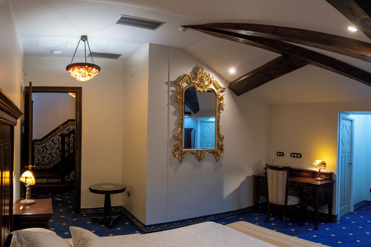 Une chambre à coucher avec un lit, un bureau, une chaise, un miroir et une lampe.