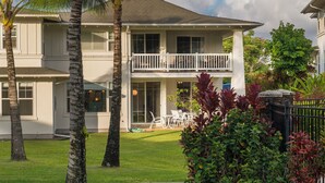 A two-story house with a balcony, surrounded by a well-maintained lawn and tropical plants. - Light and Airy North Shore Condo. Owner hosted w/on site Co-host!  (Princeville)