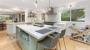 A modern kitchen with a central island, pendant lighting, and a view of the outdoors. - Stunning Marin County home with pool (San Anselmo)