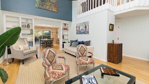 A spacious living room with a high ceiling, a dining area, and a staircase leading to an upper level. - Stunning Marin County home with pool (San Anselmo)