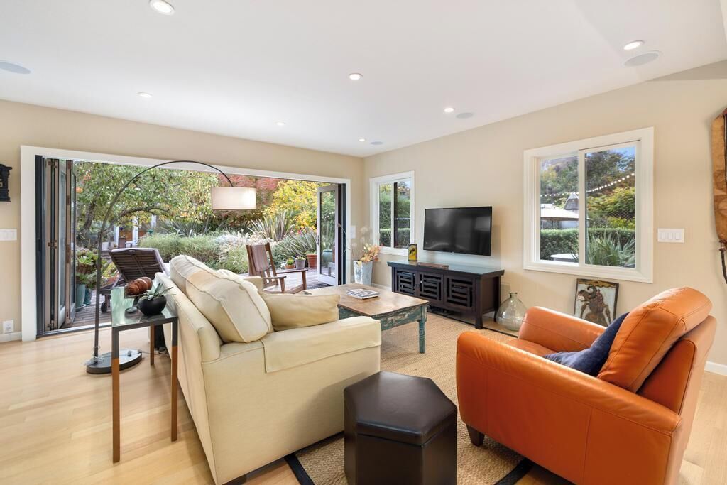 A spacious living room with a sofa, armchair, and TV.