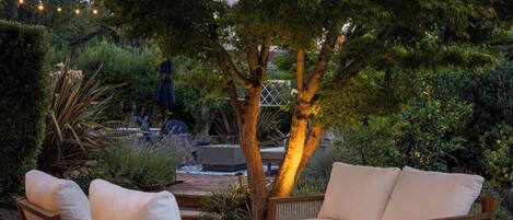 An outdoor seating area with wicker furniture, a round table, and string lights.