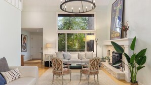 A spacious living room with a large window, a fireplace, and a chandelier. - Stunning Marin County home with pool (San Anselmo)