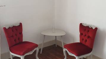 Une pièce d’angle avec deux fauteuils rouges, une petite table ronde et un tapis blanc.