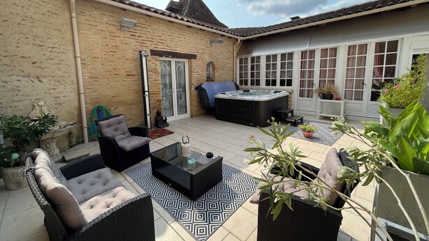 A patio area with wicker furniture, a hot tub, and potted plants. - Domaine De l Ourbise  (Razimet)