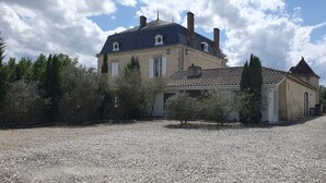 A large, historic building with a tiled roof and multiple chimneys, surrounded by trees and gravel. - Domaine De l Ourbise  (Razimet)