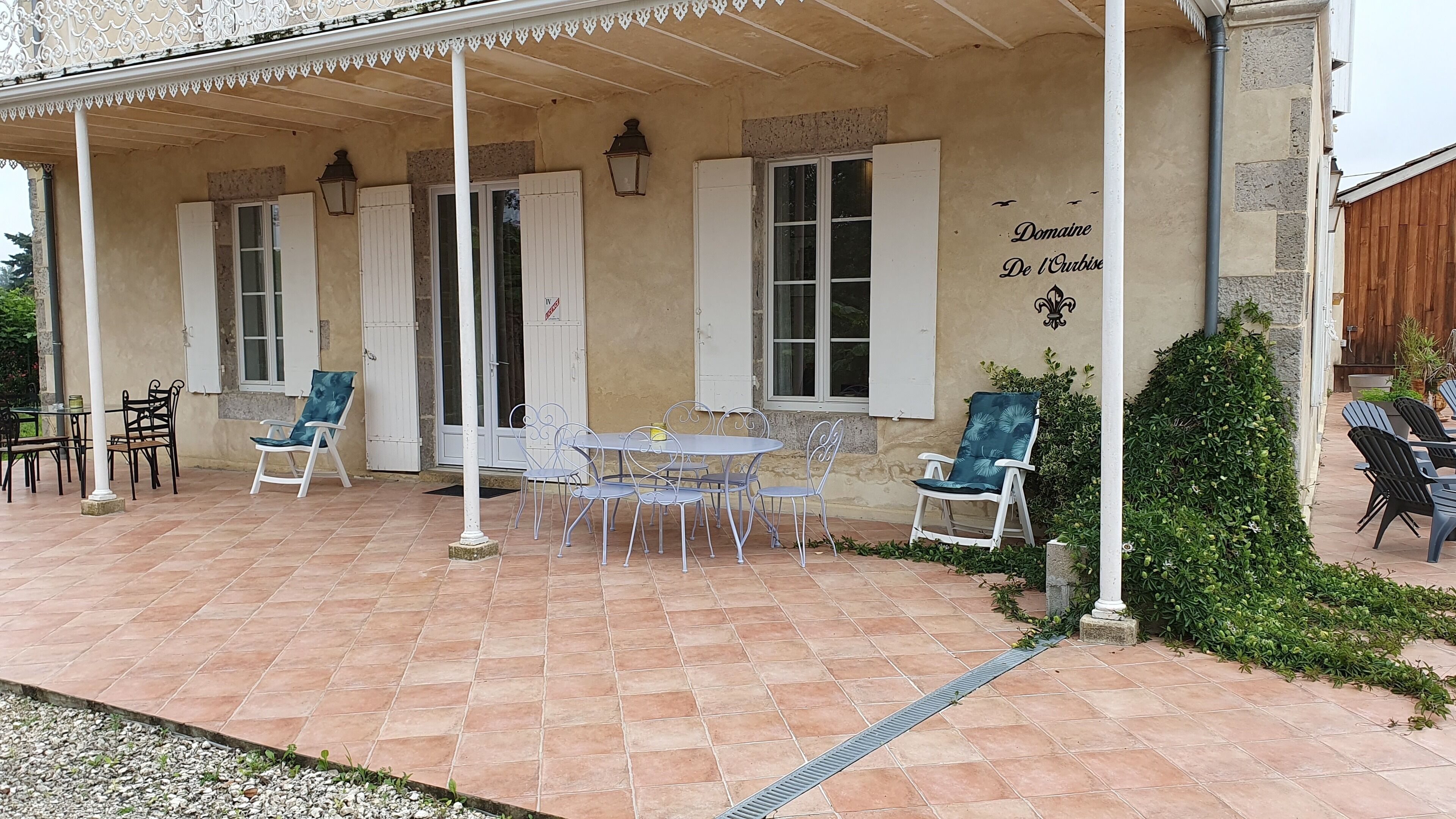Un porxo cobert amb taula i cadires, una petita zona de jardí i un rètol que diu "Domaine De L'Orbise".
