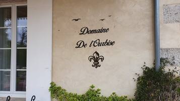 Eine Wand mit dem Schriftzug 'Domaine De l'Ourbise' und einem Fleur-de-Lis-Symbol.