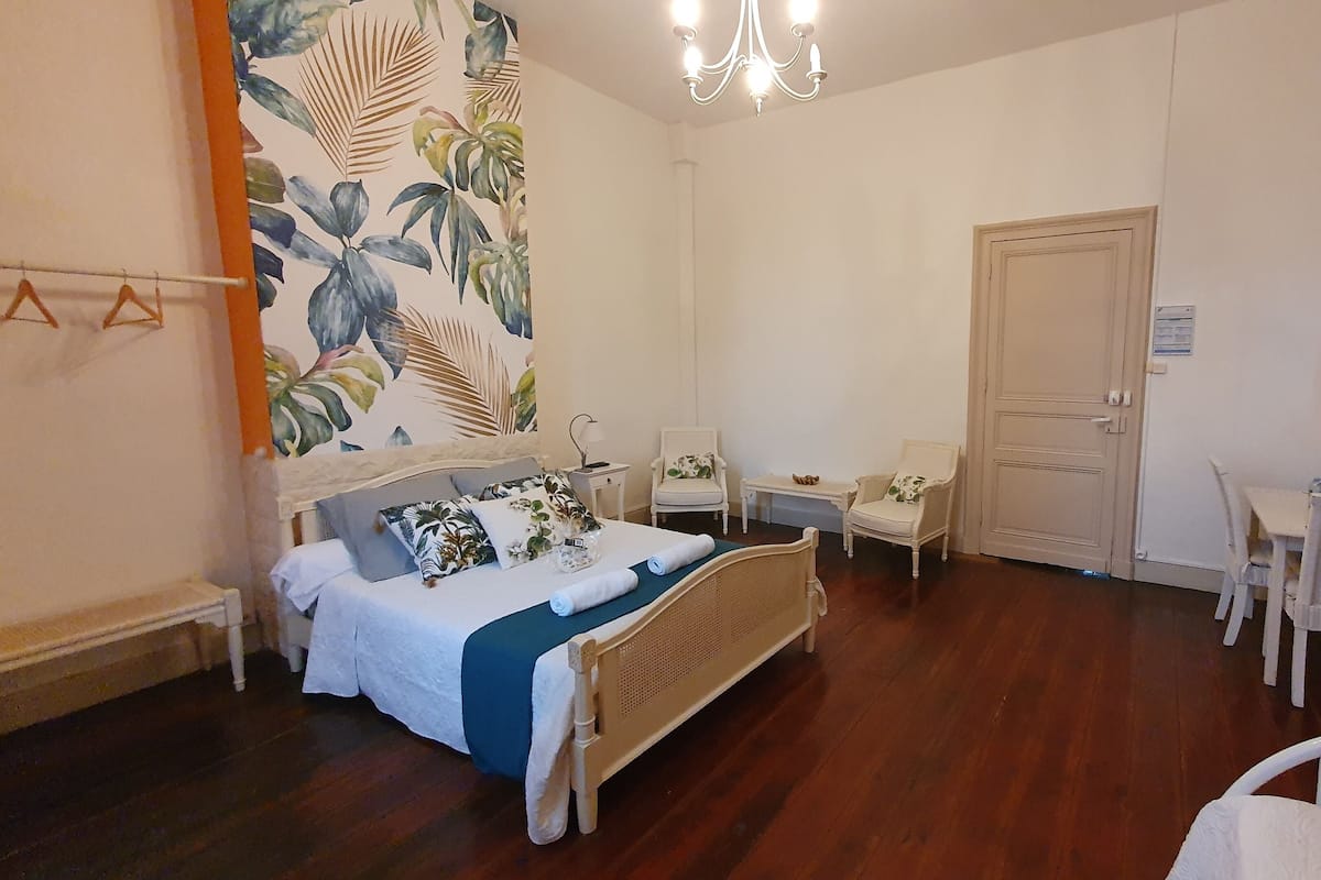 Quarto com cama, duas cadeiras, escrivaninha, porta e lustre.