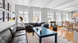Ein modernes Wohnzimmer mit Ledersofa, Couchtisch und Essbereich mit Stuhl und Tisch.
