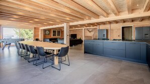 Une cuisine spacieuse dotée d’un grand îlot central, d’appareils électroménagers intégrés et d’un coin repas avec une longue table et des chaises.