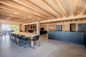 Cozinha ampla com uma ilha grande, eletrodomésticos embutidos e área de jantar com uma mesa comprida e cadeiras.