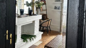 A room with a white fireplace, a black-framed mirror, a wooden bench, and a bookshelf with books and decorative items. - Magnificent T3 with panoramic seafront view (Arcachon)