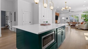 A modern kitchen with a central island, pendant lighting, and a view into the living area. - Stylish Chattanooga Retreat Minutes to Downtown (Chattanooga)